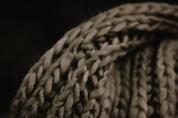 Warm gray knit scarf on black background. The texture of a wool product, an accessory for the cold...