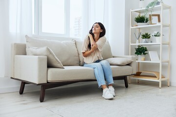 Fototapeta premium Woman sitting on sofa at home arm and shoulder pain, muscle sprain and joint pain, calcium problems in bones