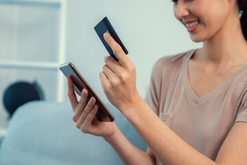 Contented young woman eagerly makes an online purchase using her smartphone. E-commerce business,...