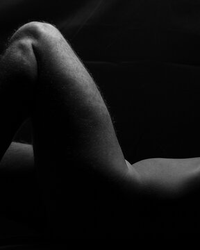 close-up of fragment from nude male model muscular naked man exposing thigh and torso with back background, vertical with copy space for advertising