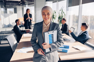 Portrait of muslim business woman is standing in meeting room of colleagues background