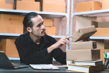 working man checking a parcel and take a note, with smiling look happy with his job. man working with new business about online shopping in home office and small store.