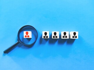 Head hunting concept on wooden cubes with magnifying glass against blue background.