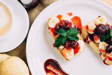 Top view of a plate with two loaves of bread with banana and red fruit cream. Food.