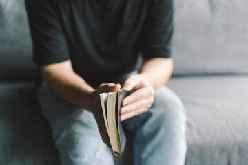 Christian man holds holy bible in hands. Reading the Holy Bible in a home. Concept for faith, spirituality and religion. Peace, hope