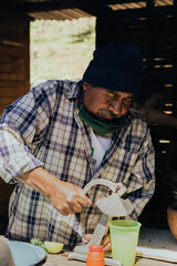 Elderly Latino man preparing lemonade on a wooden stove.