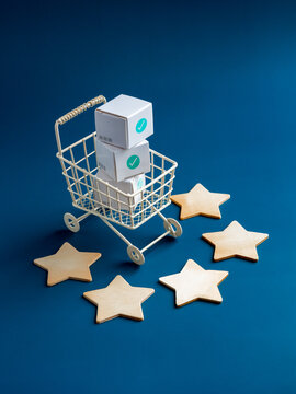 Shopping online business, e-commerce, delivery and customer review concepts. Green checkmark icon on white parcel boxes in shopping trolley cart with five stars rating on blue background, vertical.