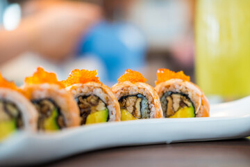 Salmon sushi roll on top with tobiko and salmon caviar. Close up