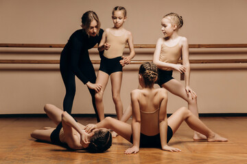 Full-length portrait of a beautiful dance teacher instructing a group of little girls in a dance...