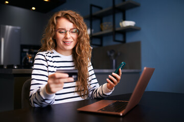 Happy woman makes purchase, payment in fintech app on phone. Shopper girl uses mobile banking app, credit card to pay for goods on black friday sale. Female in anticipation of order fullfilment.