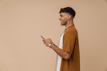 Young handsome stylish smiling man in necklace holding his phone