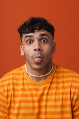 Young handsome stylish man with piercing in necklace showing tongue