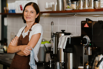 White mature barista woman smiling while working in cafe