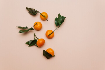 Orange tangerines with green leaves, scattered on a beige background. Clementine, mandarin. Top view. Flat lay