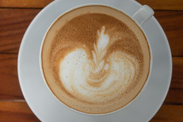 closeup hot coffee latte art cup on wood table.