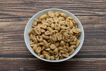 Pealed Peanuts in a bowl isolated on wooden background
