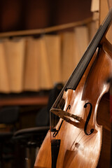 An acoustic double bass made out of wood is resting befeore a performance