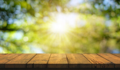 Empty wooden table are placed outdoors on green bokeh from natural leaves and sunlight. Counter display concept