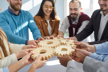 Young business people stacking wooden gears cog in office closeup, successful cooperation,...