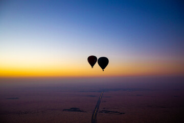 Heißluftballon Fahrt zum Sonnenaufgang am Horizont über der Wüste Dubai