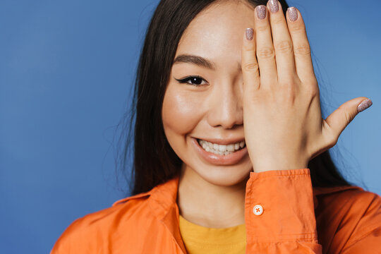 Young asian woman wearing t-shirt smiling while covering her eye