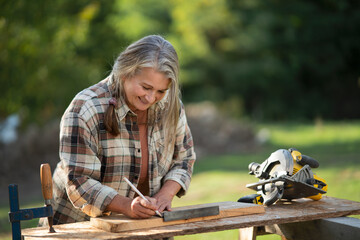 Handy female carpenter working in carpentry diy workshop outdoors. - obrazy, fototapety, plakaty