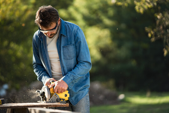 Craftsman Working With Circular Saw At Construction Site