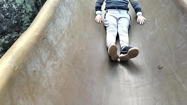Autistic boy slides down a long hill