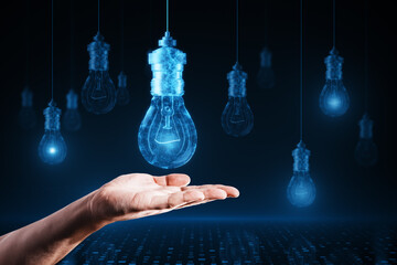 Close up of businessman hand holding glowing digital lamp hologram on dark background. Idea, innovation and future concept.