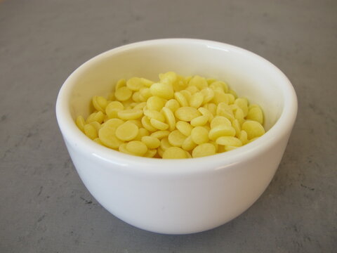 A bowl of light yellow cocoa butter chips as an ingredient for cooking and baking, chocolate making or personal care products
