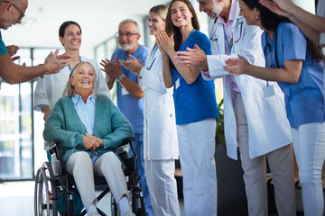 Medical staff clapping to patient who recovered from serious illness.