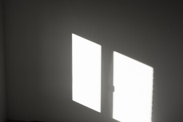 Reflection of sunlight from a window opening on the wall, abstract background with geometric lines in an empty room.