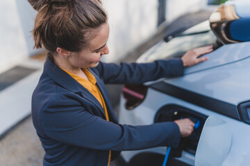 Young woman charging her electric car in home, sustainable and economic transportation concept.