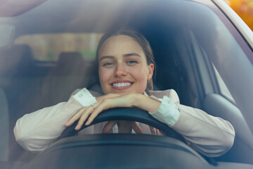 Excited young woman sitting in her car, prepared for driving.