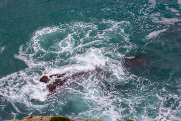A raging ocean with a funnel, vortex of blue water viewed from a cliff. Circulating water top view....