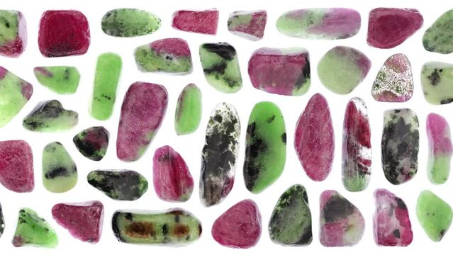 Ruby zoisite jewel stones set texture on light white isolated background. Macro closeup. Moving right seamless loop backdrop.