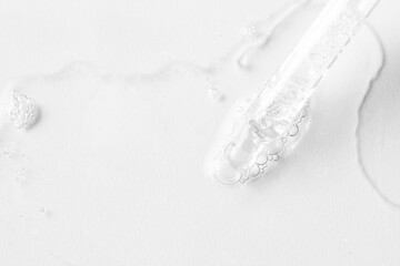 Abstract Pipette dropper  with transparent liquid drops on white background. Concept for  Laboratory investigation, medicine, science research, cosmetic and perfume industry