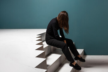 Chronic fatigue syndrome, concept. A young woman is sitting wearily on the steps, a failure when...