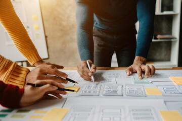  UX developer and ui designer brainstorming about mobile app interface wireframe design with customer breif and color code at modern office..