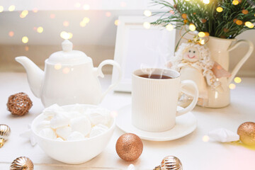   Winter, Christmas, New Year decoration composition, concept, background. White Mug, cup of hot tea, coffee, meringue, knitted plaid. Christmas lights. Christmas mood morning. Xmas greeting card.