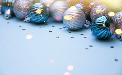 Fototapeta premium Christmas baubles on blue background. Frame border. Christmas New Year composition background blue grey silver colored. Christmas lights. Minimal concept.