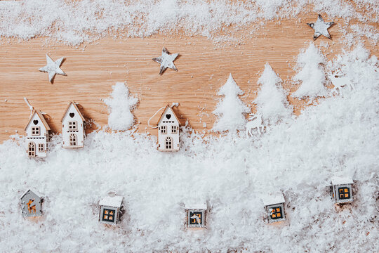 Christmas winter landscape with small houses, artificial snow, stars and lights, flat lay