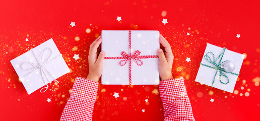 banner gift box in children's hands on a red background, presenting a gift