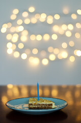 Festive birthday cake with burning candles against bright bokeh background. Greeting card. Party and holiday celebration concept