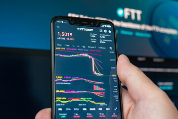 Man holding phone with FTX logo. Global fall of cryptocurrency graph - FTT token fell down on the...