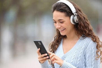 Happy woman walks listening to music in the street