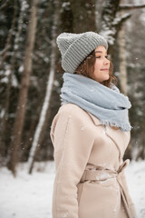 A cute girl walks through the forest in winter under the snow