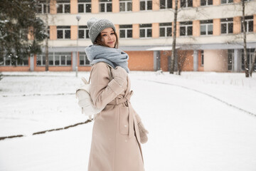 A student girl with a white backpack goes to study in winter under the snow