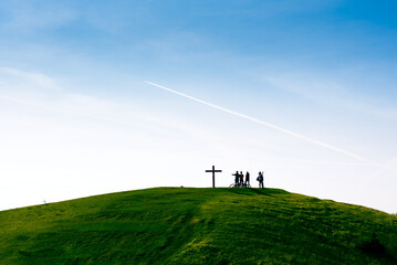 Obraz na płótnie Canvas People near the cross on a green hill