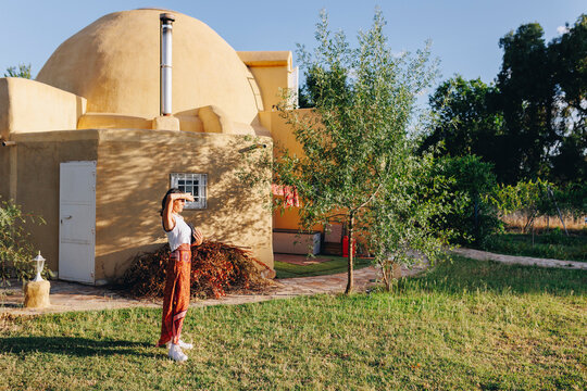 Woman shielding eyes in backyard outside geodesic dome